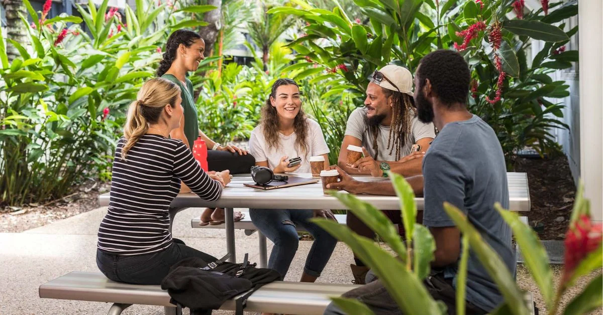 tafe-queensland-community-coffee A group of five people enjoy a friendly conversation over coffee at an outdoor table surrounded by lush greenery